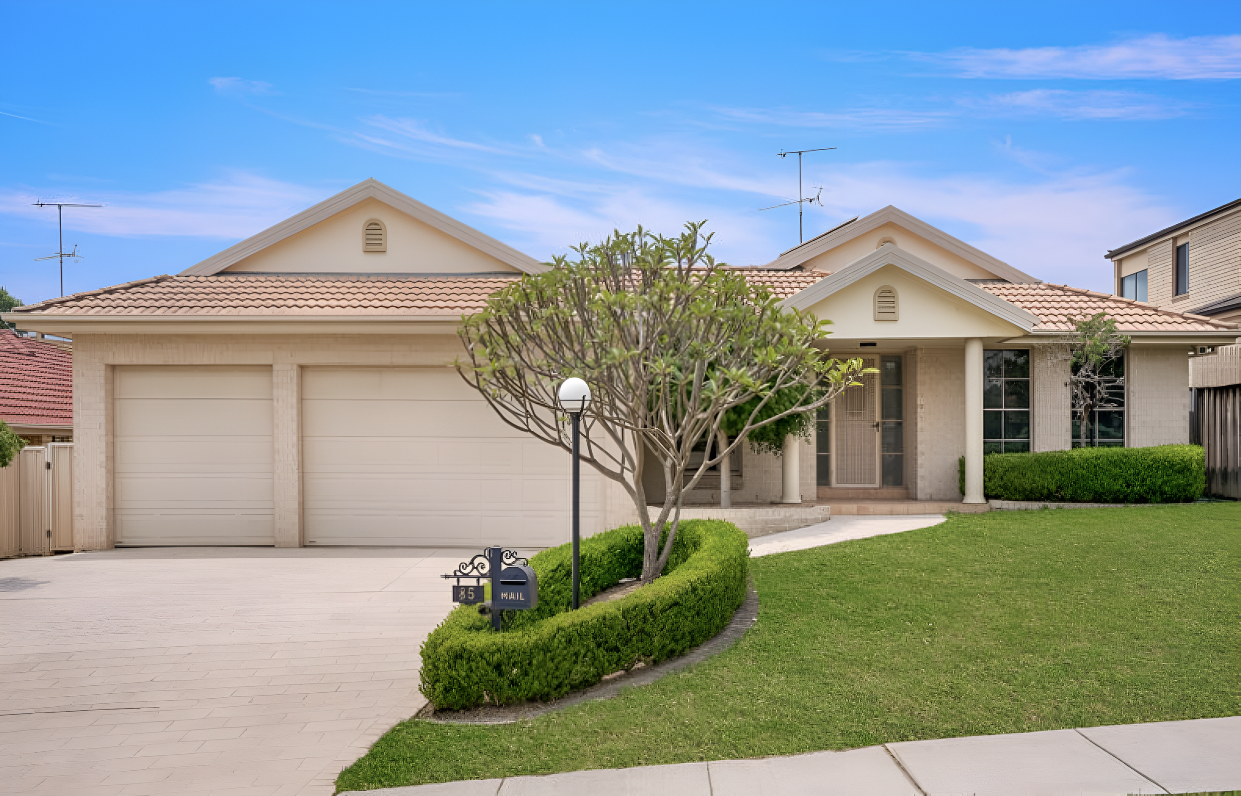 Front view of a suburban house with a two-car garage, manicured lawn, a tree, and a mailbox with the number 135.